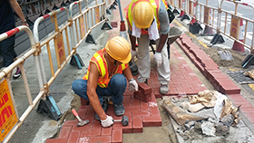 Reconstruction of footpath by laying concrete paving blocks with recycled materials